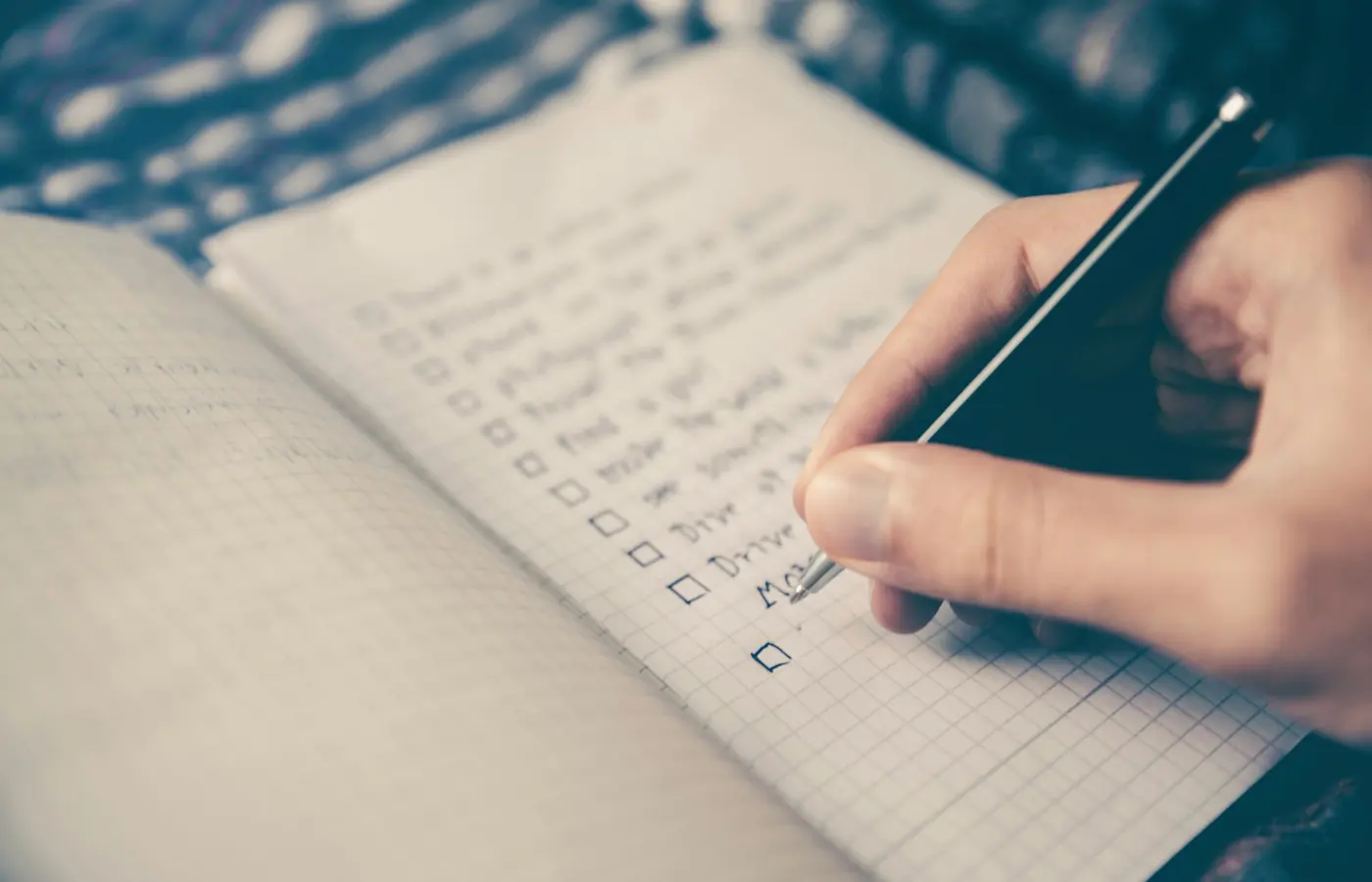 Main qui coche une liste dans un carnet, sur un bureau