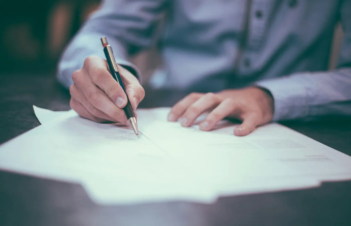 Personne en train de signer un document avec un stylo